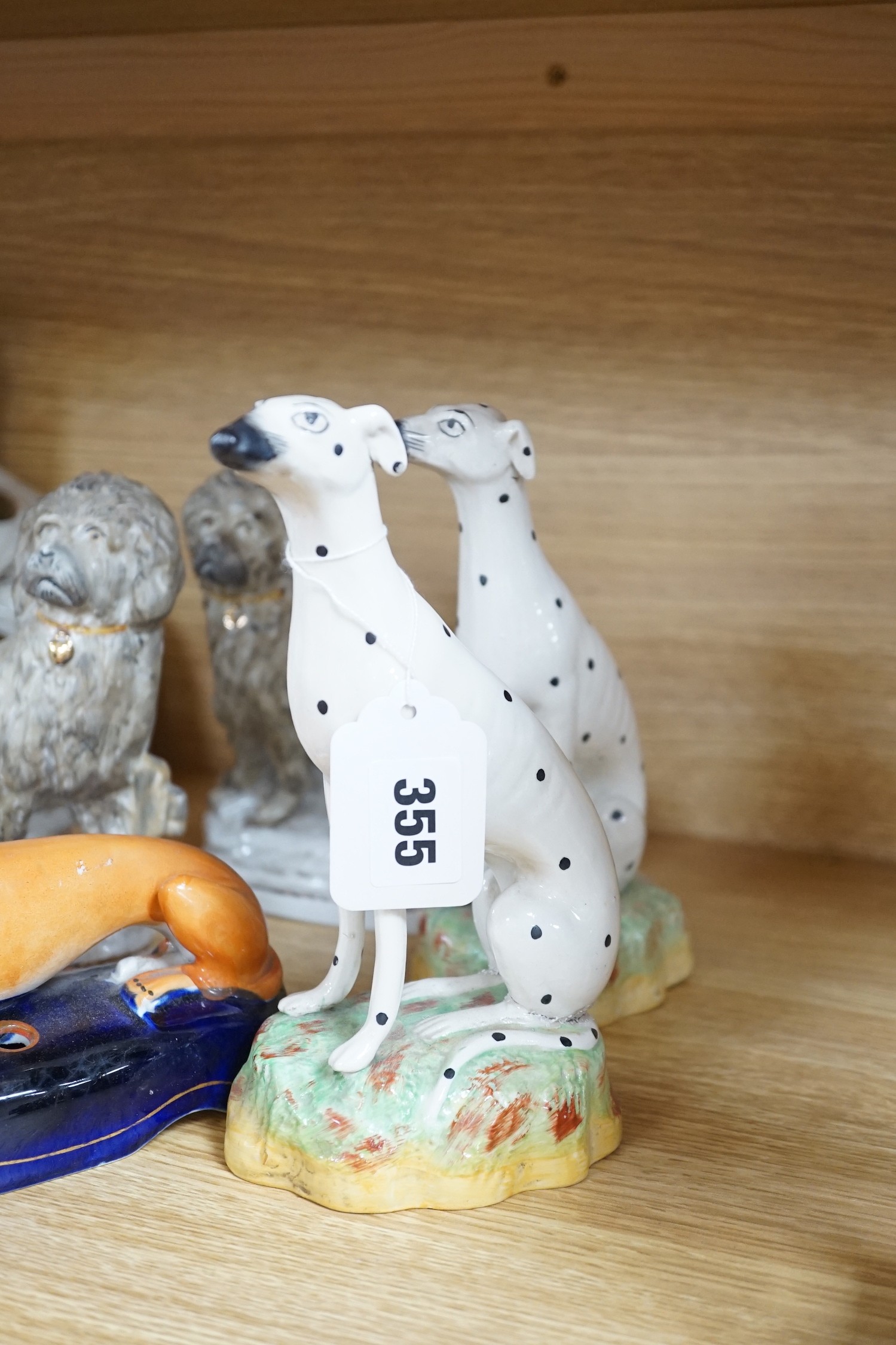 A mixed collection of mostly Staffordshire pottery models of recumbent dogs, hounds, etc. to include Dalmatians- 19.5cms high